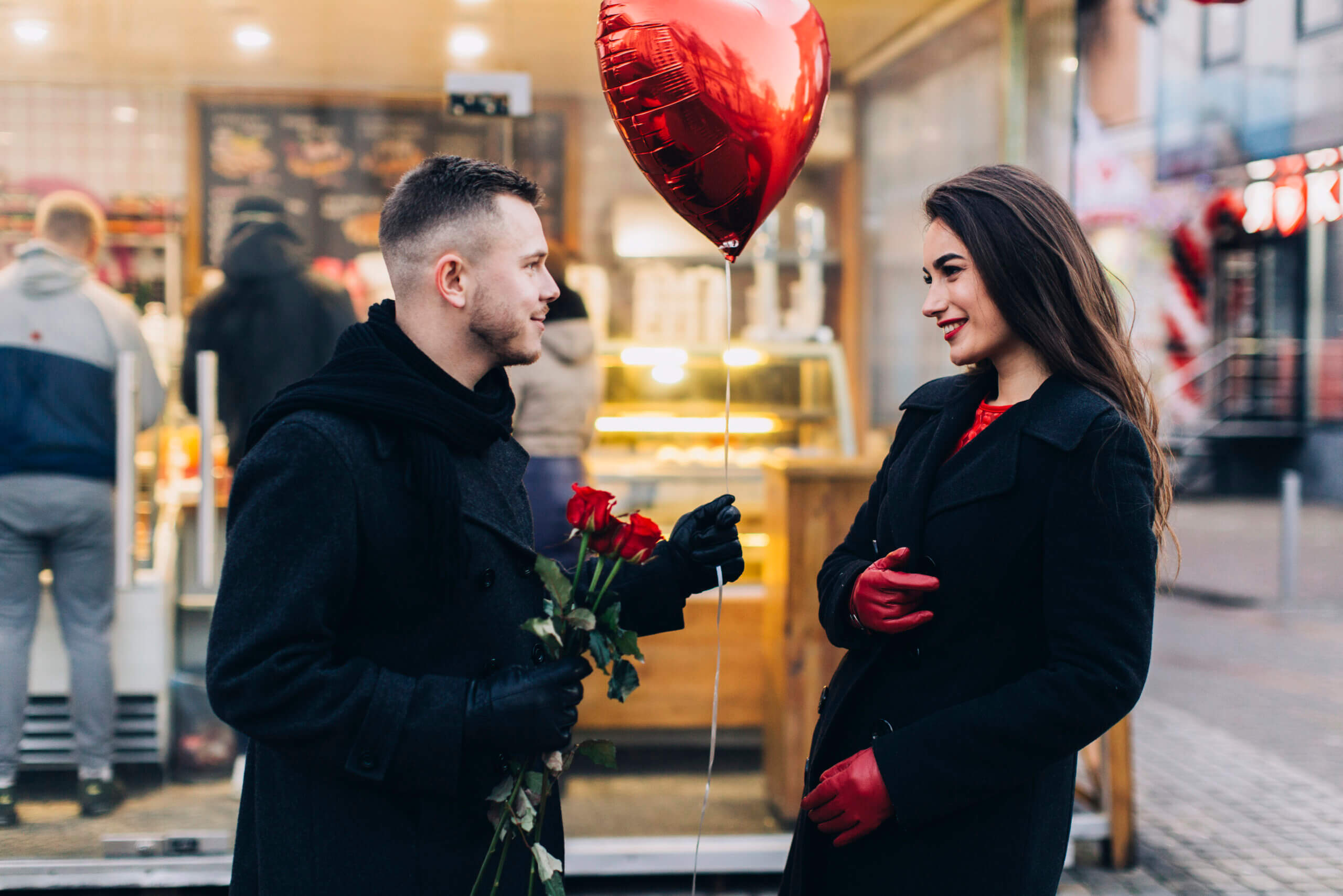 Young couple exchanging roses and a heart balloon on Valentine’s Day in London