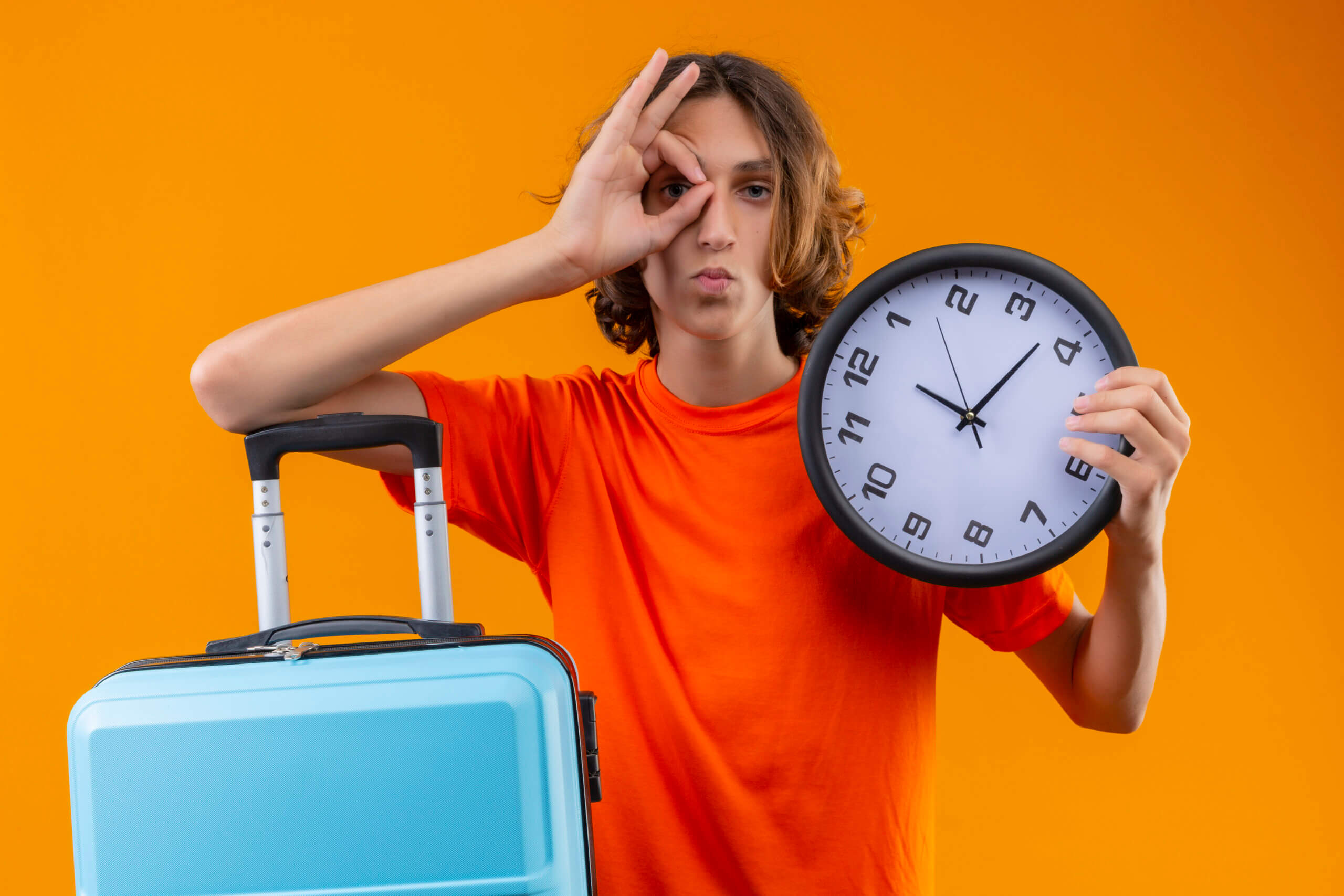 Traveller holding a wall clock beside a suitcase, emphasising the importance of timing for airport transfers