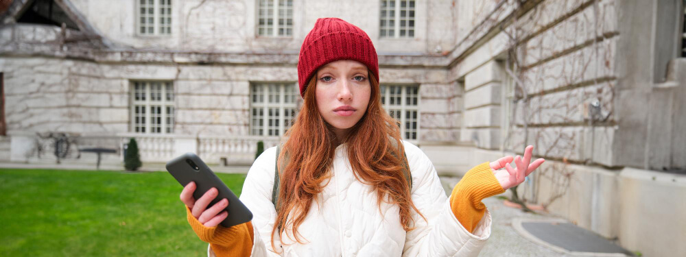 Woman looking confused at her phone while checking Google Maps for London airport directions