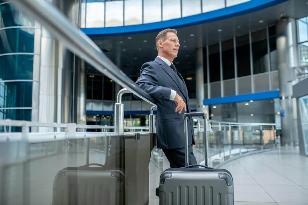 Business traveller with two suitcases navigating airport terminal, representing the challenge of relocating to London with significant luggage