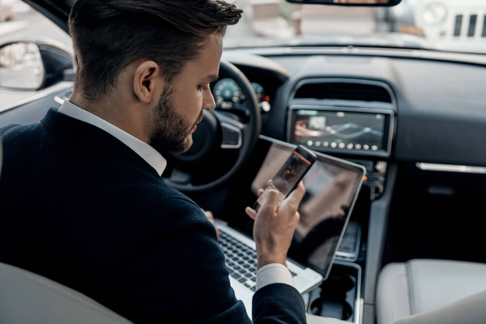Transfer driver in an executive vehicle monitoring flight status on a phone and tablet before an airport pickup